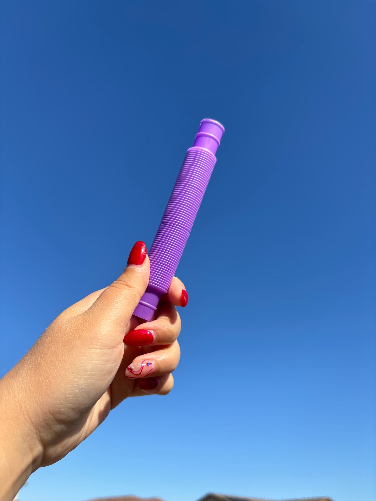 Purple pop tube being held up in front of sky background