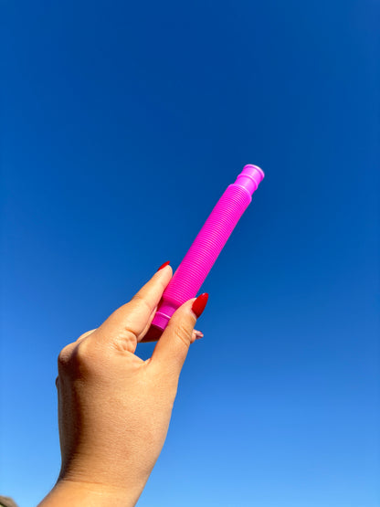 Hot Pink / Magenta pop tube being held up in front of sky background