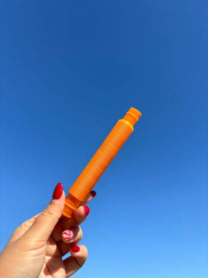 Orange pop tube being held up in front of sky background