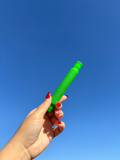 Green pop tube being held up in front of sky background