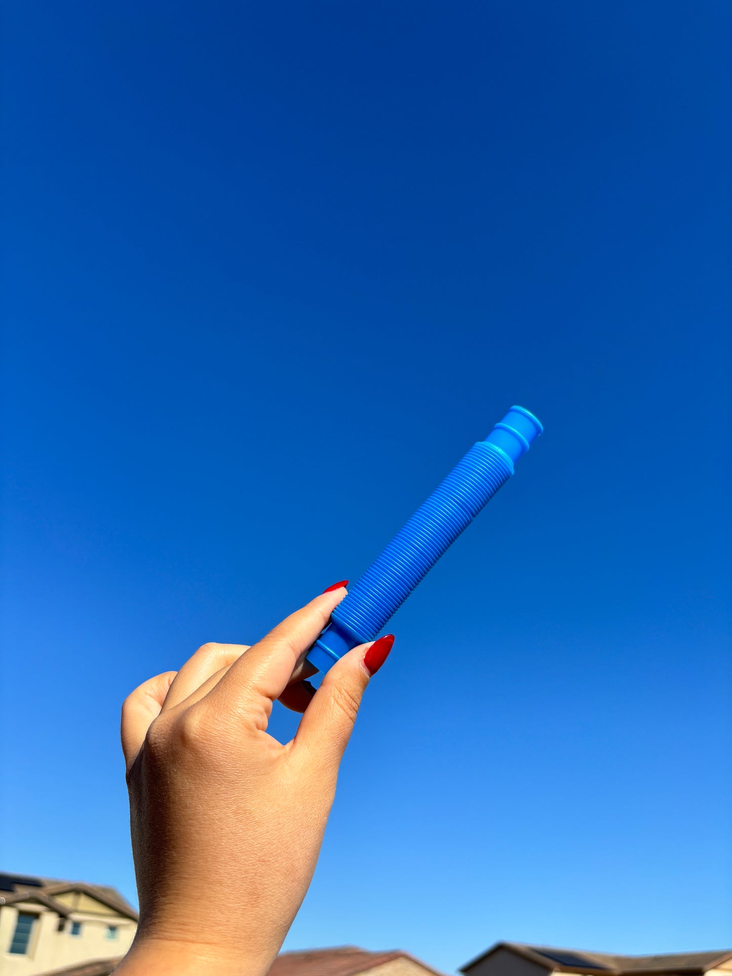 Dark blue pop tube being held up in front of sky background