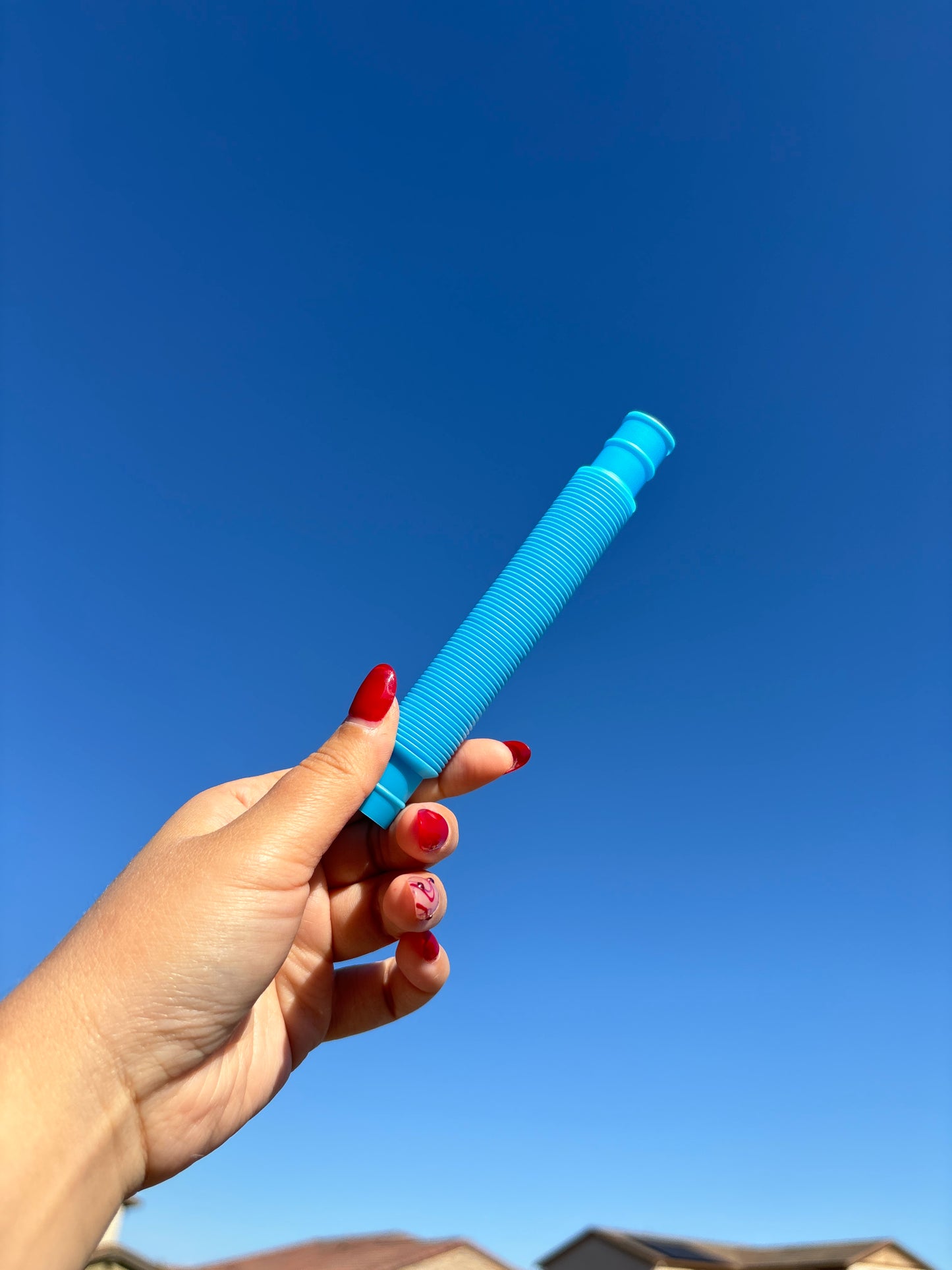 Blue pop tube being held up in front of sky background
