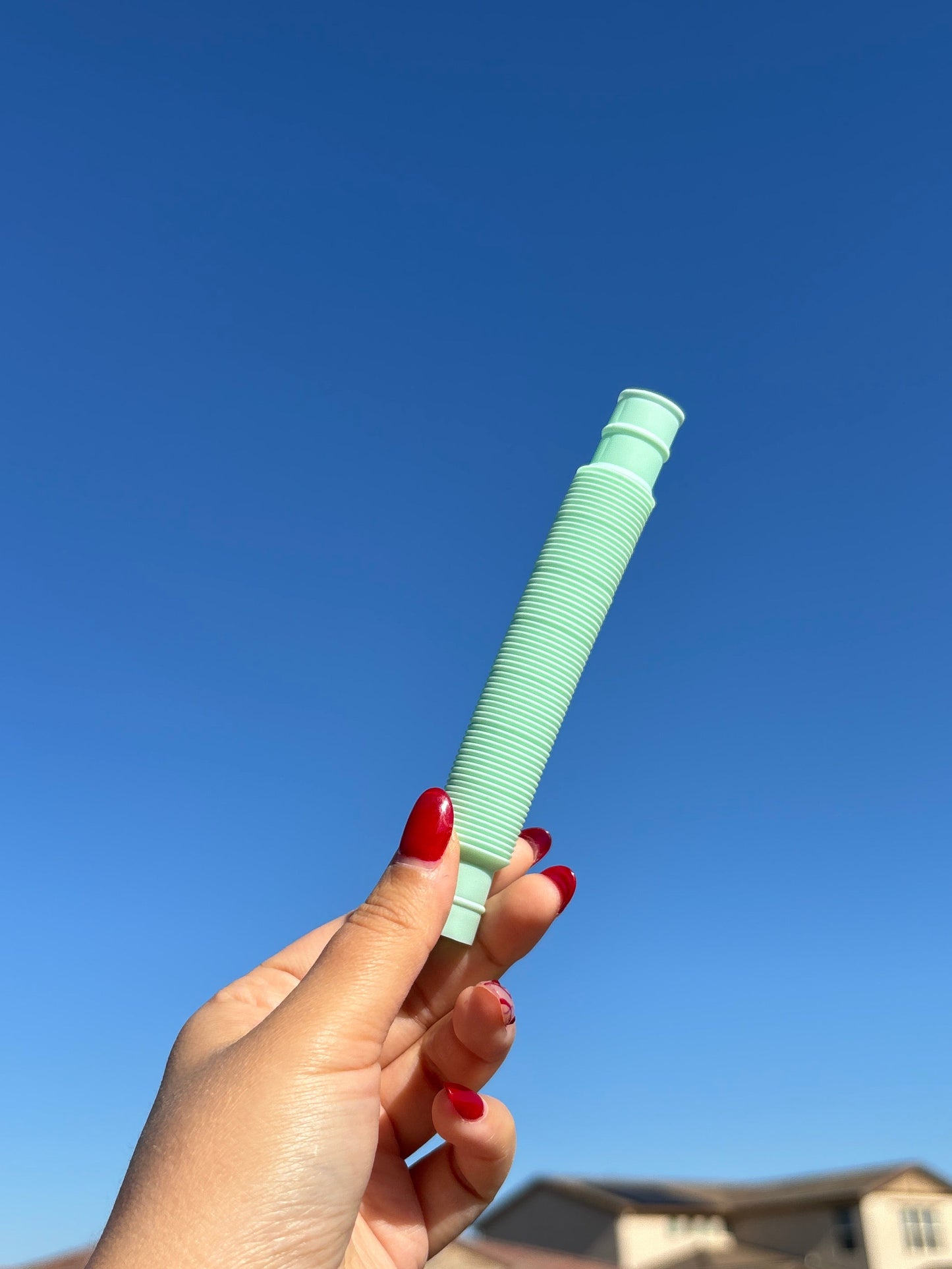 Mint Green pop tube being held up in front of sky background