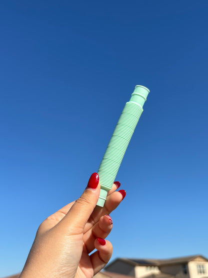 Mint Green pop tube being held up in front of sky background