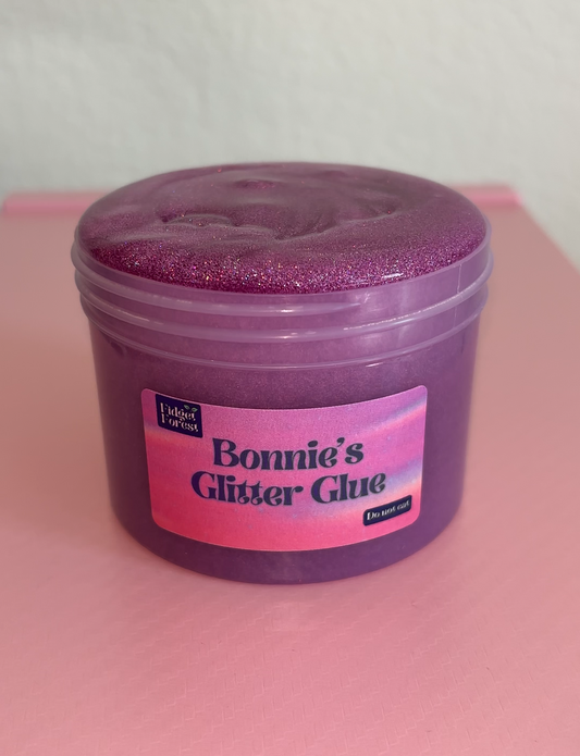 Purple Glitter slime in container labeled “Bonnie’s Glitter Glue” with pink background 