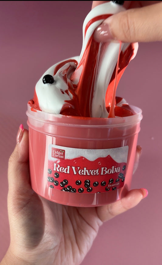Red and White Slime labeled “Red velvet boba” in a container, held by a hand against a pink background