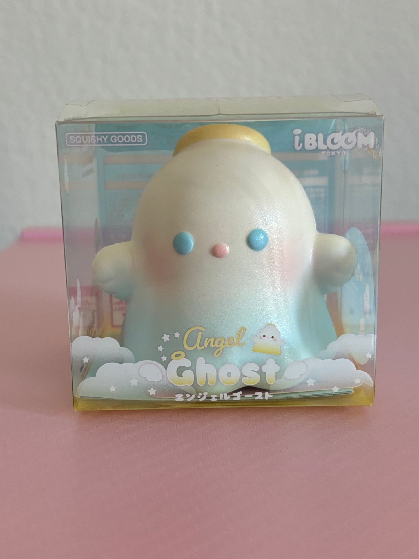 An iBLOOM Angel Ghost squishy toy in its original packaging, featuring a cute pastel-blue angel ghost with blue eyes and a yellow halo, labeled 'Angel Ghost'.