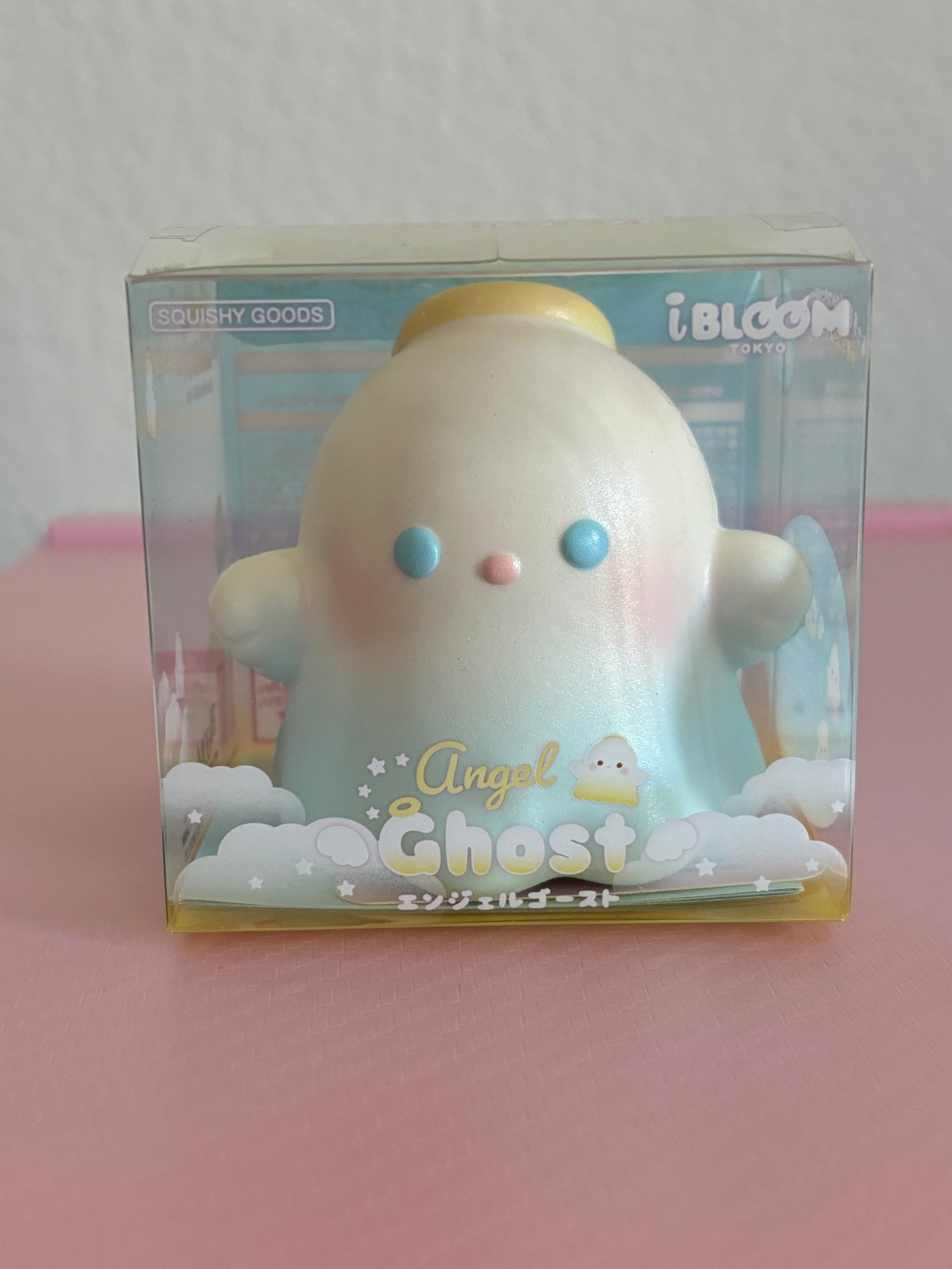 An iBLOOM Angel Ghost squishy toy in its original packaging, featuring a cute pastel-blue angel ghost with blue eyes and a yellow halo, labeled 'Angel Ghost'.
