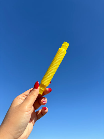 Yellow pop tube being held up in front of sky background