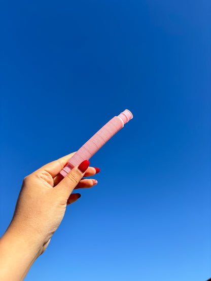 Light pink pop tube being held up in front of sky background
